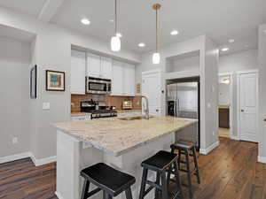 Kitchen with sink, stainless steel appliances, an island with sink, and white cabinets