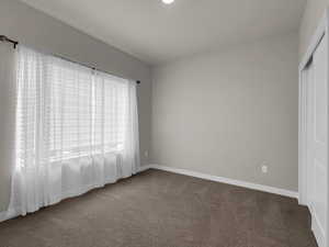 Unfurnished bedroom featuring a closet and dark colored carpet