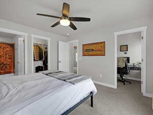 Carpeted bedroom featuring a spacious closet, ceiling fan, and a closet