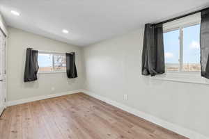 Empty room featuring vaulted ceiling and light hardwood / wood-style flooring