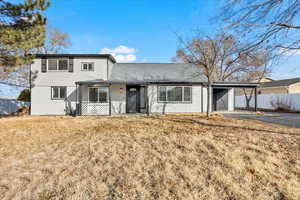 View of property featuring a carport and a front lawn