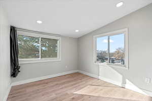 Unfurnished room featuring lofted ceiling and light hardwood / wood-style flooring