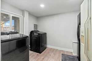 Washroom featuring washing machine and dryer, light hardwood / wood-style floors, and electric panel