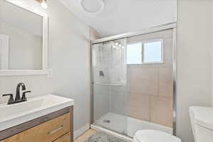 Bathroom with vanity, toilet, a shower with shower door, and tile patterned flooring