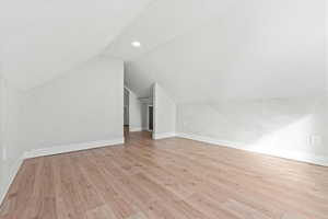 Bonus room with lofted ceiling and light hardwood / wood-style floors