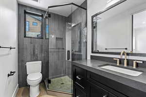 Bathroom featuring walk in shower, tile patterned floors, vanity, and toilet