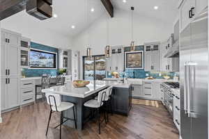 Kitchen with a T-shaped island, luxury fixtures, a breakfast bar area, dual-fuel range, hood and refrigerator