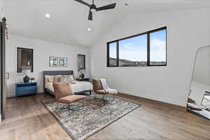 1st primary bedroom with hardwood floors, vaulted ceiling, and ceiling fan