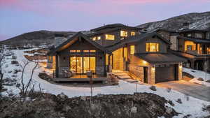 Snow covered property with a garage, a mountain view, and a deck