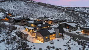 Snowy aerial view of back of model home and view at sunset.