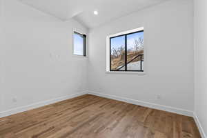 Empty room featuring wood-type flooring and vaulted ceiling