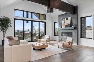 Living room featuring hardwood flooring, beam ceiling, a fireplace, high vaulted ceiling and views from deck.