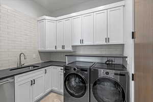 Laundry area with washing machine and clothes dryer, dishwasher and sink.