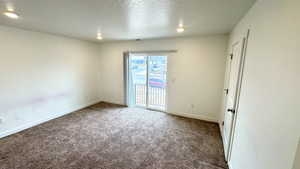 Empty room with a textured ceiling and carpet flooring