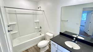 Full bathroom featuring hardwood / wood-style flooring, vanity, toilet, and bathing tub / shower combination