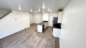 Kitchen featuring wood-type flooring, sink, white cabinets, and a textured ceiling