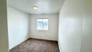 Carpeted empty room featuring a textured ceiling