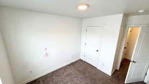 Unfurnished bedroom with dark colored carpet