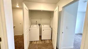 Laundry area featuring independent washer and dryer and light colored carpet