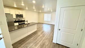 Kitchen featuring white cabinetry, stainless steel appliances, sink, and light wood-type flooring