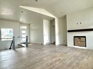 Unfurnished living room with lofted ceiling and light hardwood / wood-style flooring