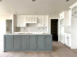 Kitchen with a kitchen island, white cabinetry, light wood-type flooring, gray cabinetry, and a textured ceiling