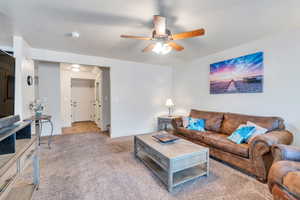 Carpeted living room with ceiling fan