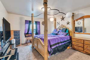 Bedroom with decorative columns, carpet flooring, and a textured ceiling