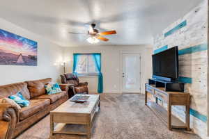 Carpeted living room featuring a textured ceiling and ceiling fan