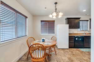 Kitchen featuring pendant lighting, sink, dark brown cabinets, black dishwasher, and white refrigerator