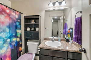 Bathroom with vanity, a shower with shower curtain, and toilet