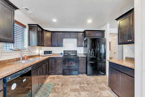 Kitchen featuring dark brown cabinetry, sink, and black appliances