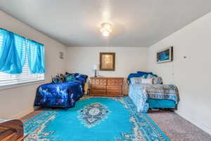 Carpeted bedroom with ceiling fan and a textured ceiling