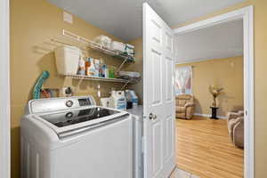 Laundry room with washer and dryer, hardwood / wood-style floors, and a textured ceiling