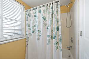 Bathroom featuring shower / tub combo with curtain and plenty of natural light