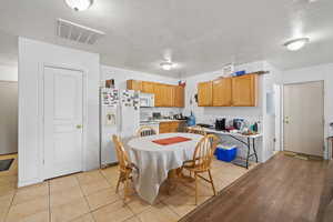 Kitchen with light wood finished floors, white appliances, visible vents, and light countertops