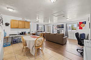 Dining space with attic access, a textured ceiling, and light tile patterned floors