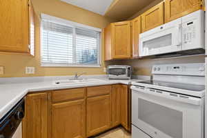 Kitchen featuring sink, light tile patterned floors, and white appliances