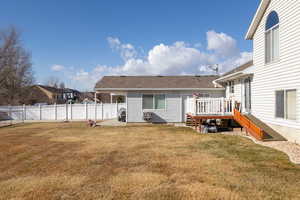 Rear view of house featuring a wooden deck and a lawn