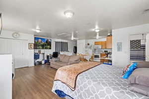 Bedroom featuring wood finished floors and white refrigerator with ice dispenser