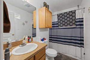 Bathroom with a shower with shower curtain, toilet, and vanity