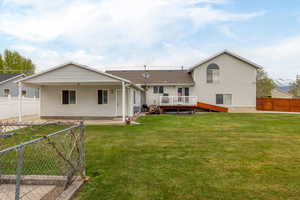 Back of property featuring a lawn, a fenced backyard, roof with shingles, and a deck