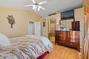 Bedroom with connected bathroom, vaulted ceiling, and light wood-type flooring