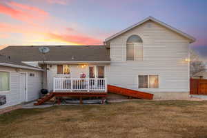 Back house at dusk featuring a yard and a deck