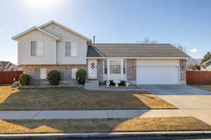 Split level home featuring a garage and a front lawn