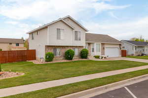 Tri-level home with a front lawn, brick siding, and fence