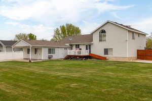 Rear view of property featuring a yard, fence, and a deck