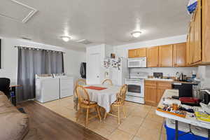 Kitchen with washer and clothes dryer, light tile patterned flooring, visible vents, white appliances, and light countertops