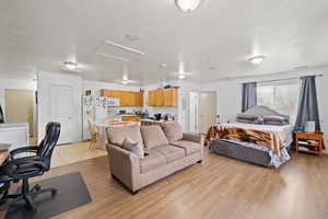 Bedroom with attic access, visible vents, light wood finished floors, and white fridge with ice dispenser