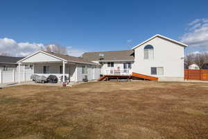 Back of property with a wooden deck and a lawn